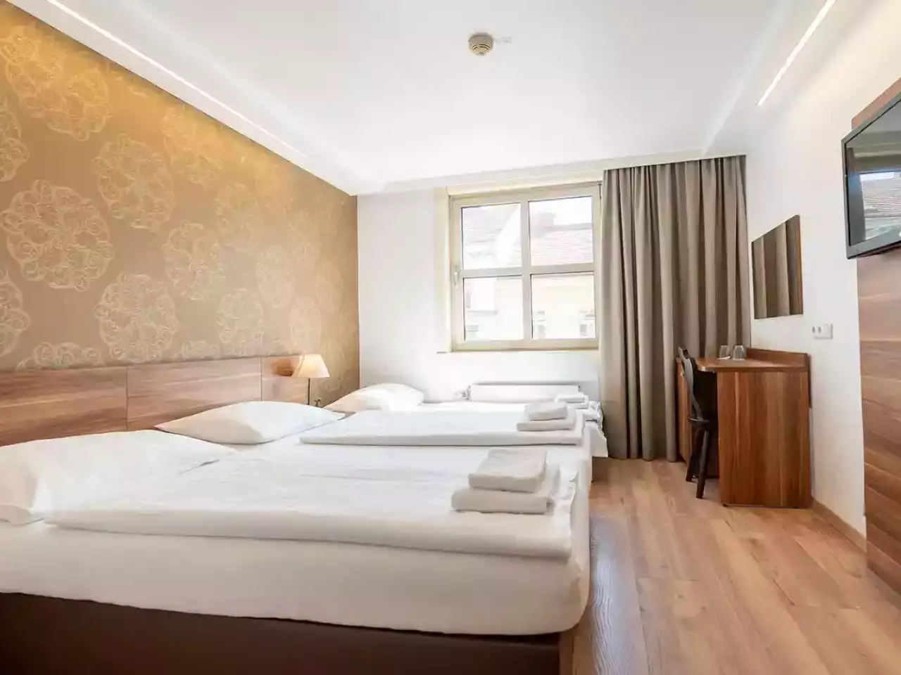 Dreibettzimmer mit Fenster und Schreibtisch
